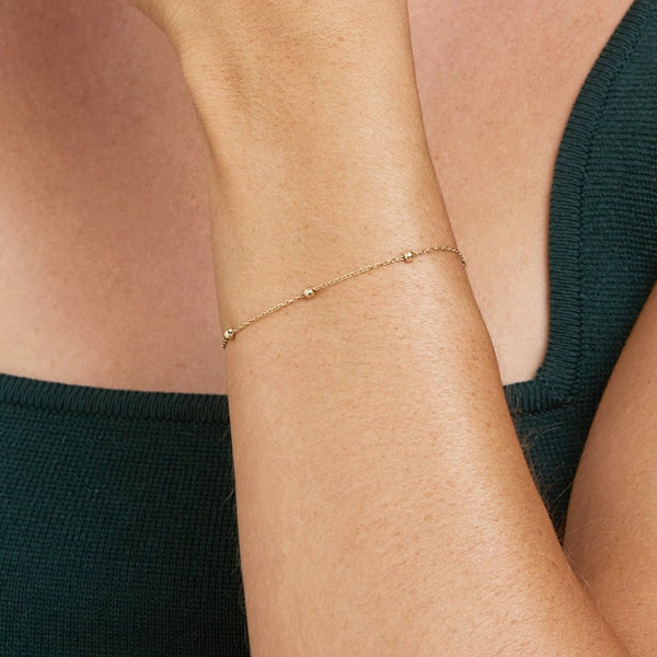 The Essential Ball Bracelet for day to night wear is made of 14 karat gold. The bracelet features solid gold balls aligned on a delicate gold chain