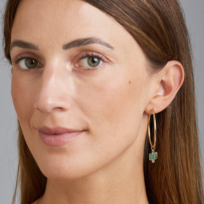 Our two piece 14 karat gold hoop earrings feature the Cactus Charms with handset emerald stones. The two charms are different and add a playful and unique look to your eargame. Take off the charm and wear the essential hoops on its own. 